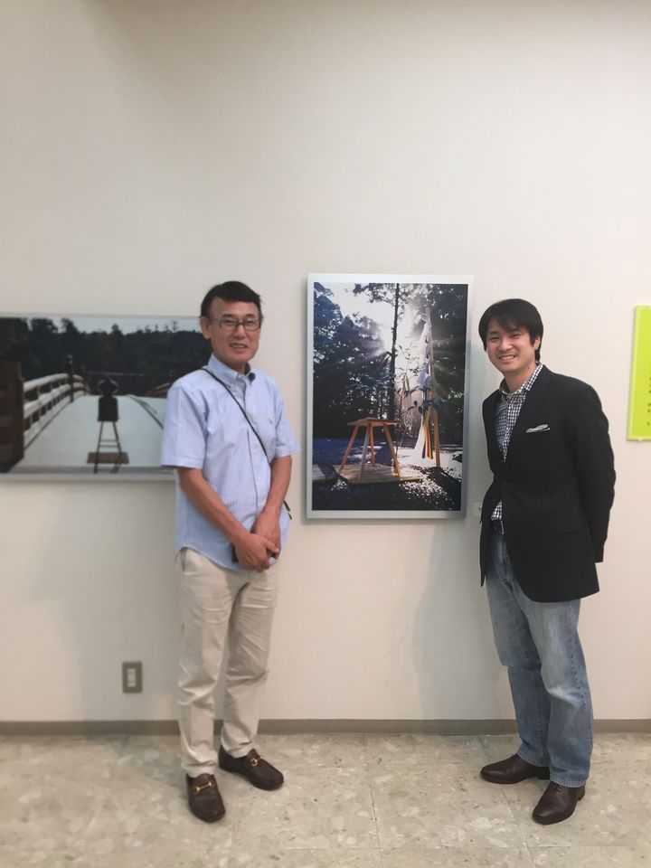 写真展で作品の前に立つ