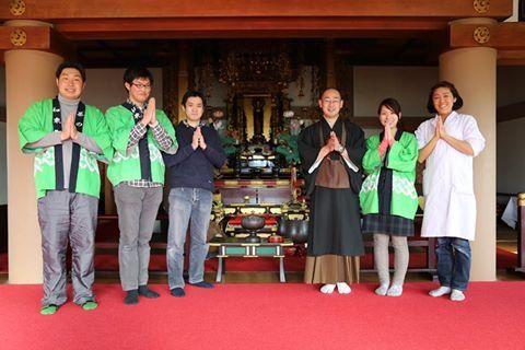 寺の本堂で手を合わせる参加者と僧侶