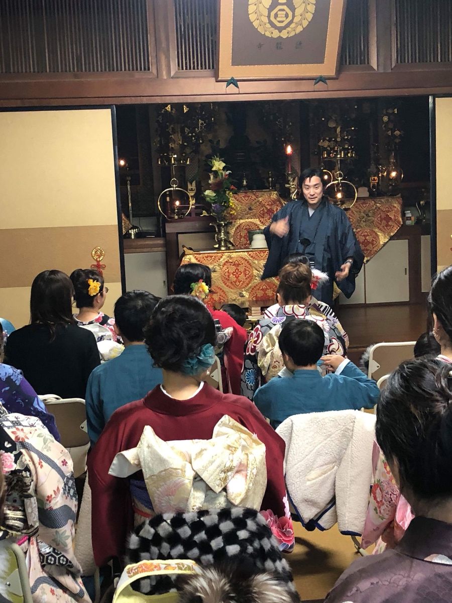 寺の本堂で、着物姿の参加者に日本の文化について話す種田成昭